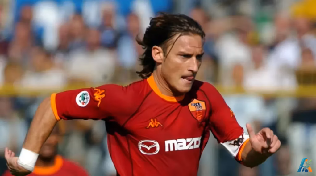 Francesco Totti mengenakan jersi merah AS Roma merayakan gol di lapangan sepak bola.