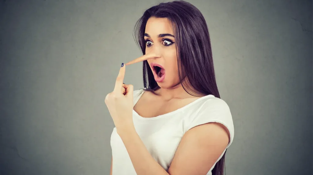 Wanita ekspresi terkejut dengan hidung panjang seperti Pinokio menunjuk wajahnya, konsep berbohong atau hoax.