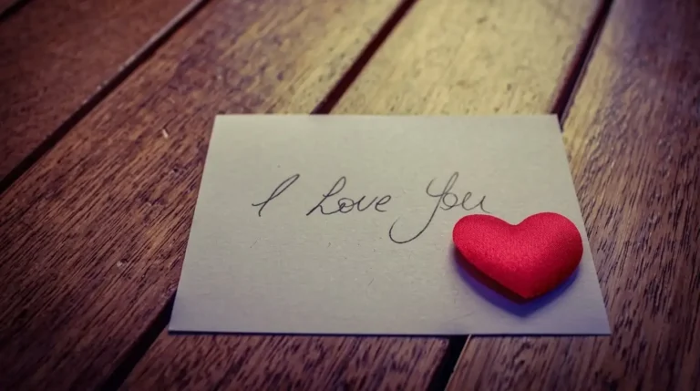 Kartu ucapan dengan tulisan tangan I Love You dan hiasan hati merah di atas meja kayu untuk artikel surat cinta seorang pengusaha
