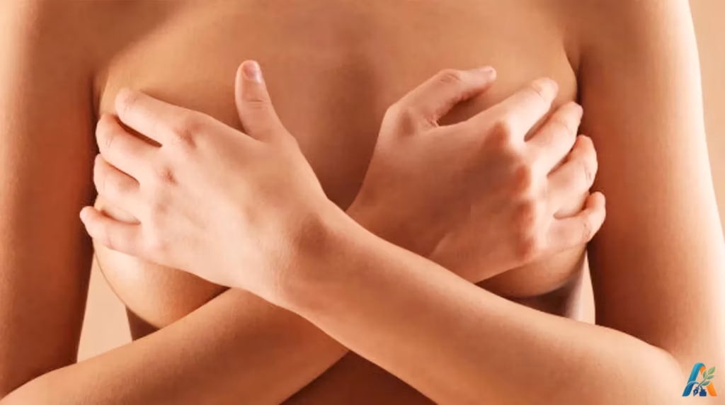 Wanita menyilangkan tangan menutupi payudara dengan latar belakang polos.