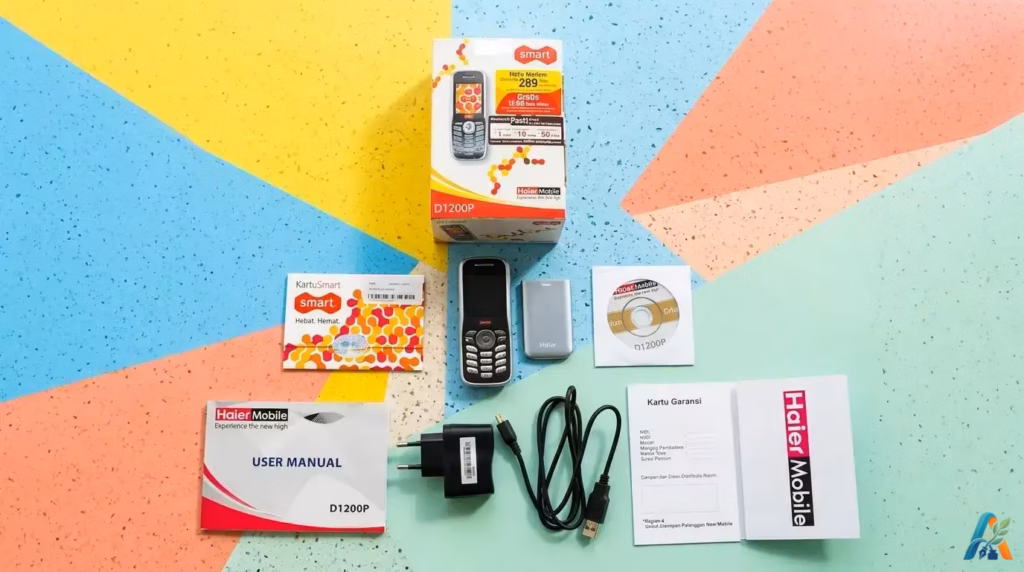 Paket penjualan ponsel Smart Haier D1200P baru lengkap dengan buku panduan dan kabel USB di atas latar warna warni.