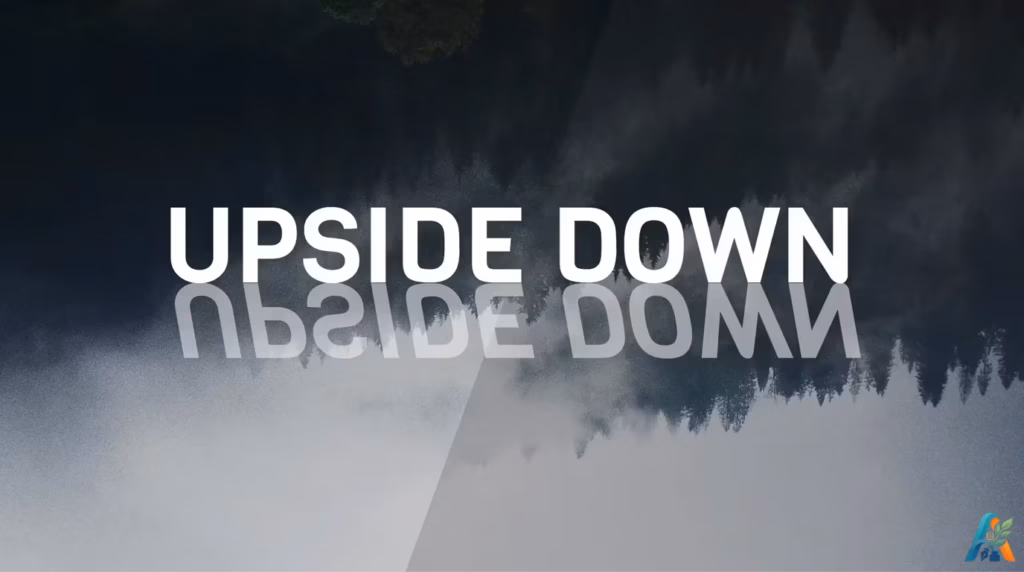Tipografi teks UPSIDE DOWN dengan efek refleksi terbalik di atas latar belakang siluet hutan pinus kabur, dari file upside-down.webp