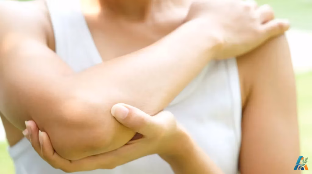 Wanita memegang siku tangan yang sakit atau cedera dengan latar belakang buram