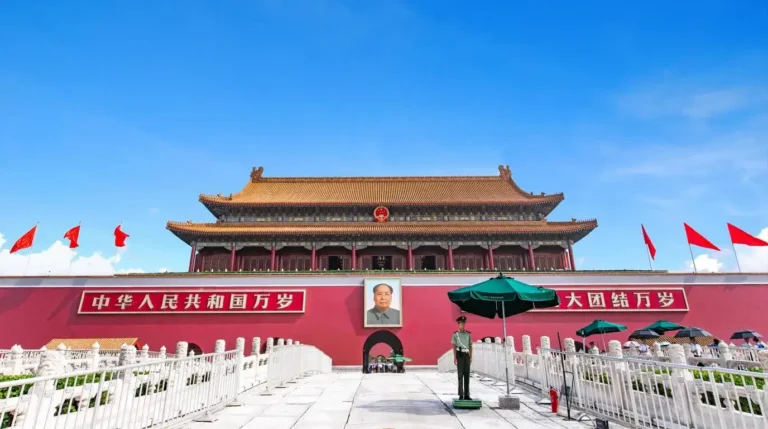 Gerbang Tiananmen yang ikonik dengan dinding merah dan atap emas di Beijing, Tiongkok, di bawah langit biru yang cerah dan jernih.