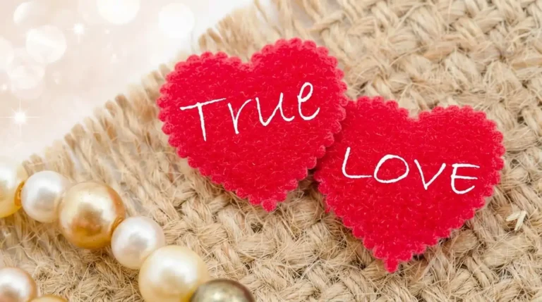 Dua hiasan hati merah bertuliskan True Love di atas kain goni berdampingan dengan gelang mutiara