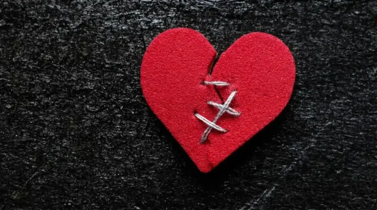 Konsep fixing a broken heart dengan simbol hati merah yang retak dan dijahit menggunakan benang putih