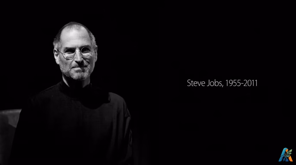 Foto hitam putih Steve Jobs mengenakan pakaian turtleneck hitam dengan teks kenangan Steve Jobs 1955-2011