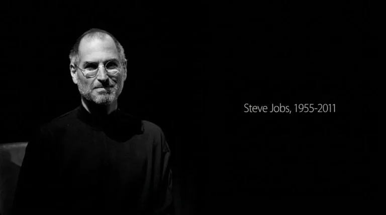 Foto hitam putih Steve Jobs mengenakan pakaian turtleneck hitam dengan teks kenangan Steve Jobs 1955-2011