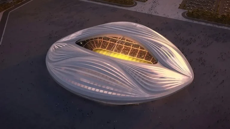 Stadion Al Janoub Qatar tampak atas dengan arsitektur futuristik putih berbentuk dhow saat senja dan lampu lapangan menyala.