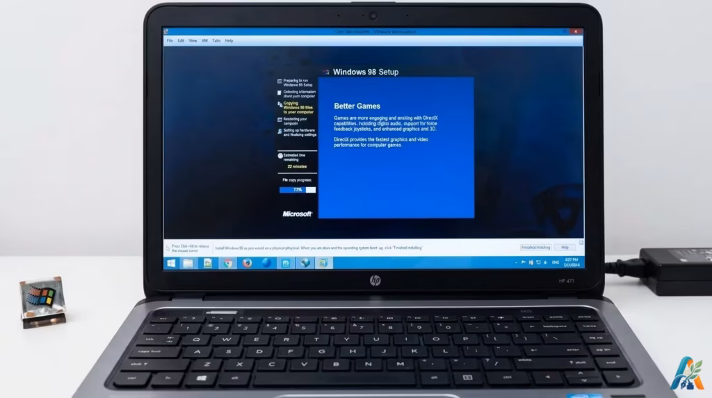 Layar laptop modern menampilkan proses instalasi sistem operasi klasik Windows 98 melalui mesin virtual dengan latar belakang biru khas.