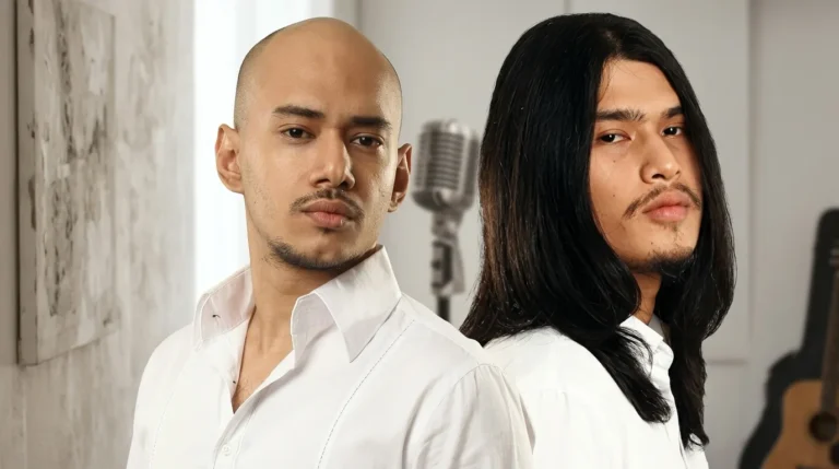 Potret dua pria musisi, satu berkepala plontos dan satu berambut panjang, mengenakan kemeja putih dengan latar belakang mikrofon dan gitar.