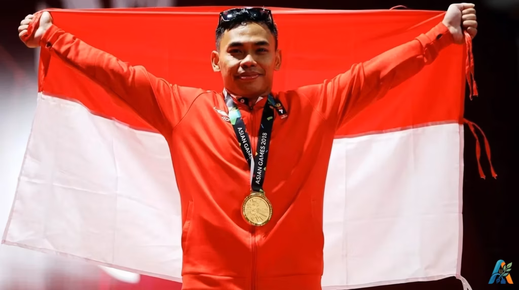 Atlet Indonesia Eko Yuli Irawan merayakan kemenangan dengan bendera merah putih setelah meraih medali emas di Asian Games, simbol kebanggaan bangsa.