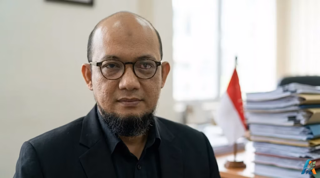 Novel Baswedan di ruang kerja dengan bendera Merah Putih dan tumpukan berkas dokumen, potret realistik
