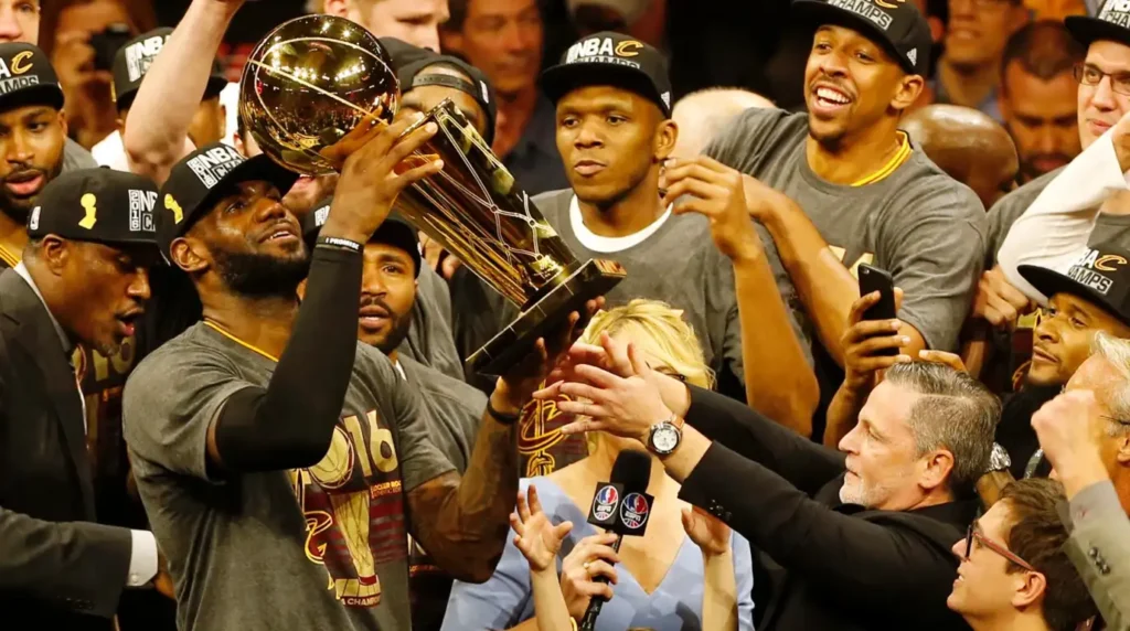 LeBron James mengangkat trofi juara NBA 2016 bersama rekan setimnya di Cleveland Cavaliers dalam perayaan kemenangan