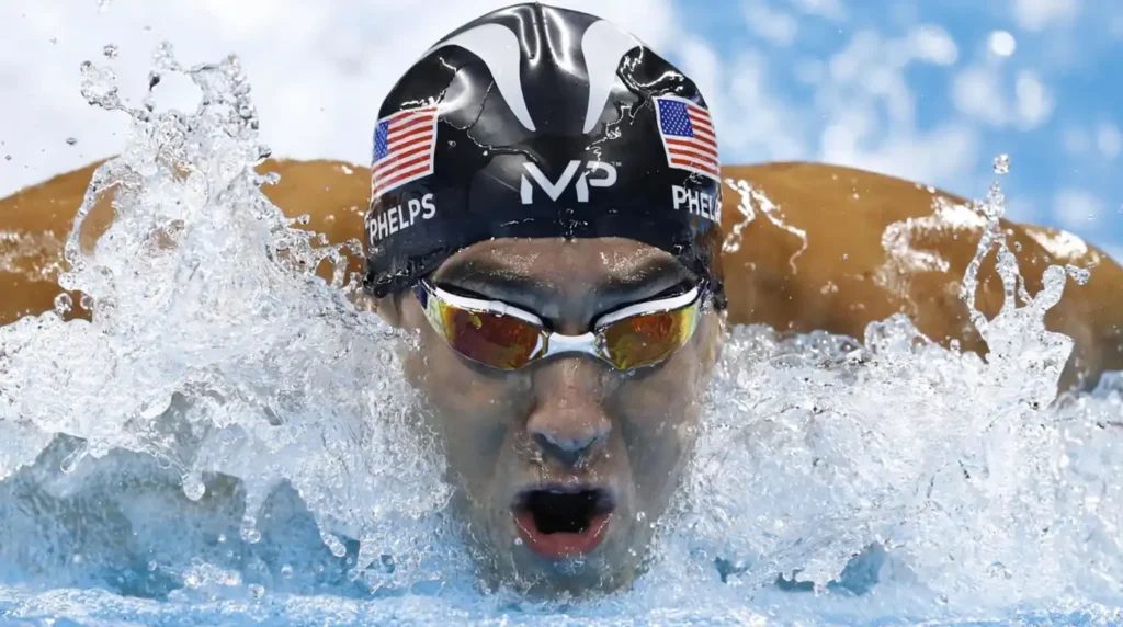 Michael Phelps berenang gaya kupu-kupu dengan intens dengan topi renang berbendera Amerika Serikat