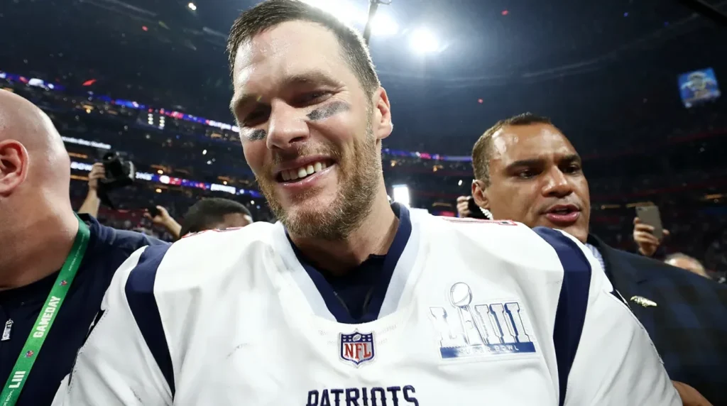 Tom Brady tersenyum gembira setelah memenangkan Super Bowl mengenakan jersey New England Patriots