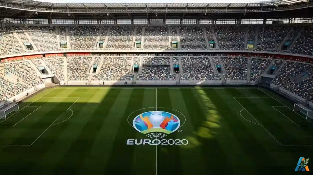 Stadion sepak bola dengan penonton yang dibatasi dan kursi kosong, menggambarkan penyelenggaraan turnamen olahraga di masa pandemi