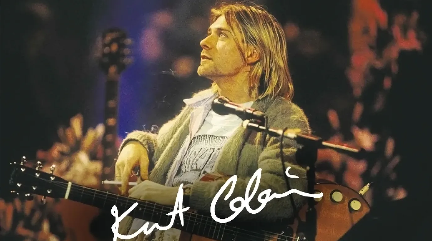 Kurt Cobain memangku gitar akustik dengan tanda tangan putih pada penampilan MTV Unplugged