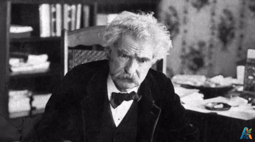 Potret hitam putih Mark Twain duduk di ruang kerja dengan rambut putih ikal khasnya