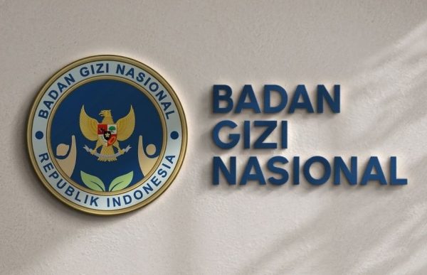 Foto profesional papan nama bertuliskan "BADAN GIZI NASIONAL" dalam huruf timbul berwarna biru tua di dinding interior bertekstur krem. Di sebelah kiri tulisan, terdapat logo bundar resmi "Badan Gizi Nasional Republik Indonesia" berwarna biru-emas dengan lambang Garuda Pancasila di tengahnya. Bayangan lembut dari dedaunan jatuh di sisi kanan dinding.