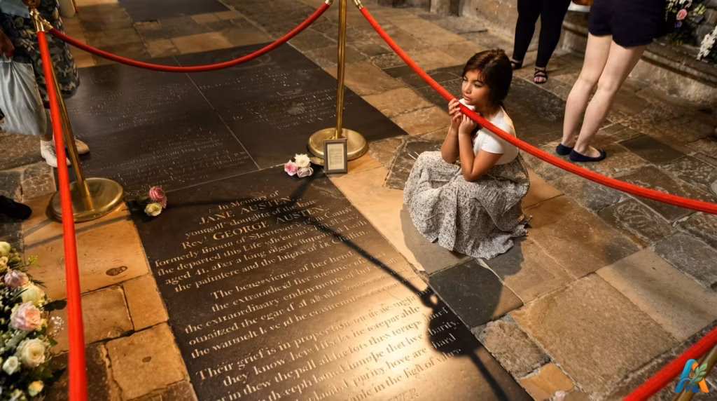 Seorang wanita muda berdoa di dekat batu nisan Jane Austen di lantai Winchester Cathedral, dikelilingi tali pembatas merah.